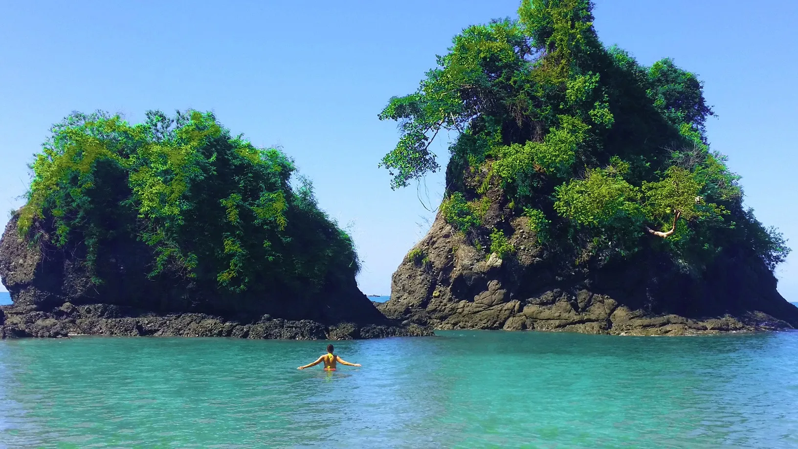 Guest swimming between two rock islands off Manuel Antonio beach